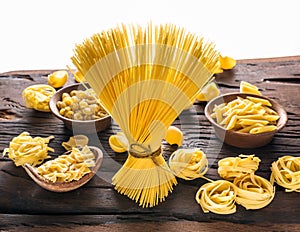 Different pasta types on wooden table. White background
