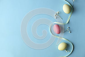 Different pastel color Easter eggs laid and arranged in beautiful composition with white wildflowers. Greeting card with copy text