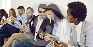 Group of happy diverse friends using mobile phones and sharing a laugh over a funny video