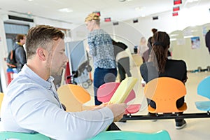 Different people sitting in waiting room hospital