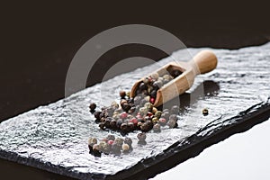 Different pepper spices on a black slate. Ingredients for cooking. Healthy eating concept. Various spices on dark background. Heal