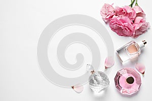 Different perfume bottles and flowers on background, top view