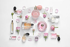 Different perfume bottles and flowers on white background