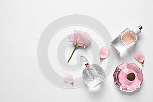 Different perfume bottles and flowers on white background