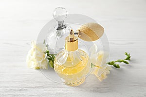 Different perfume bottles and flowers on white background