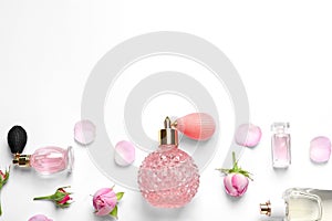 Different perfume bottles and flowers on white , top view