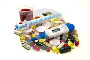 Different pills, medications with medicine with a syringe and with thermometer on white background closeup.