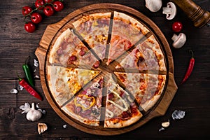 Different pizza slices on a round wooden Board