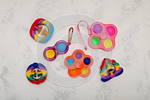 Different popular colorful children`s toys Spinner, Simple dimple, Pop it and Snapperz toys on light grey background. Top view,