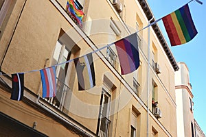 Different pride flags strung between buildings downtown Madrid, Spain. LGBTQ friendly district Chueca