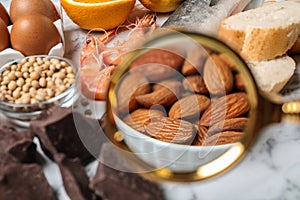 Different products with magnifier focused on almonds. Food allergy concept