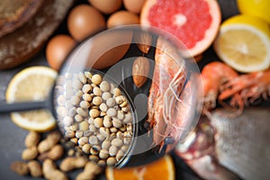 Different products with magnifier focused on soy beans and shrimps. Food allergy concept