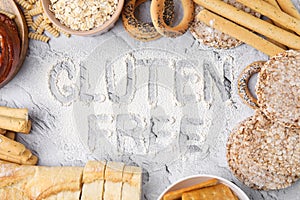 Different products and phrase Gluten free written with flour on light grey table, flat lay