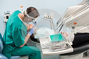 Different professional dental instruments, on the blurred background dentist is treating patient in dental clinic