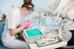 Different professional dental instruments, on the blurred background dentist is treating patient in dental office