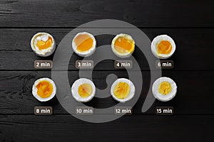 Different readiness stages of boiled chicken eggs on black wooden table, flat lay
