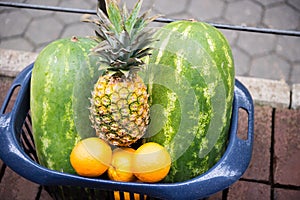 Different ripe fruits in a plastic basket on pavement