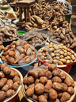 Different root vegetables and potatoes for sale from buckets on local market in Cameroon, Africa