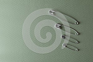 Different safety pins on green background, flat lay. Space for text