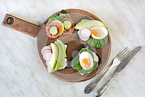 Different sandwiches with vegetables, eggs, avocado, tomato, rye bread on light marble table. Top view. Appetizer for party. Flat