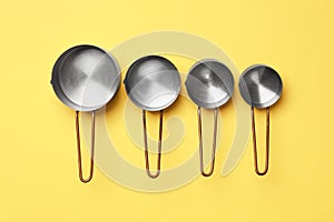 Different saucepans on yellow background, flat lay. Cooking utensils