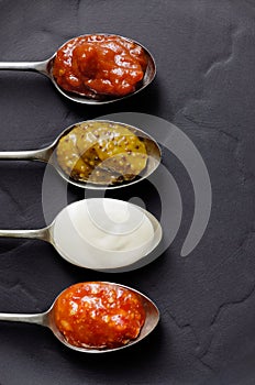 Different sauces and jams on spoons photo