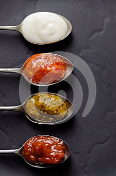 Different sauces and jams on spoons photo