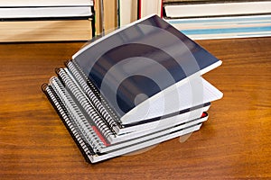 Different school exercise books stack on table against the books