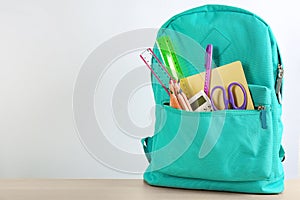 Different school stationery in backpack on table against white background, space for text. Back to school
