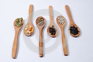 Different seeds -maize, squash, coffee, pepper, rice, sunflower- in wooden spoons on a white surface