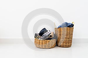 Different shape of wicker basket full of laundry clothes in clean white wall background inside bedroom.