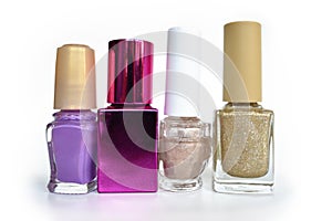 Different shaped bottles with purple, pink and shimmering golden color nail polish on white background