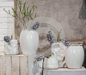 Different shapes of modern white vases with flower composition on a whitewashed wooden box