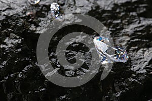 Different shiny diamonds on wet stone surface. Space for text