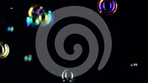Different size and color soap bubbles fly close up. Slow motion. Black backgrounds