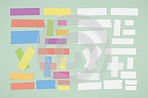 Different size colorful and white sticky paper, adhesive, masking tape stuck on green background