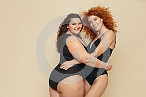 Different Size. Diversity Women Portrait. Hugging Female Friends Posing On Beige Background.