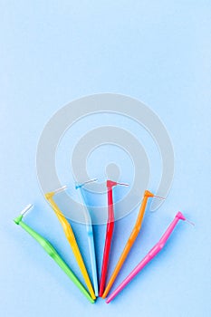 Different size interdental brush angles on blue background, vertical, copy space