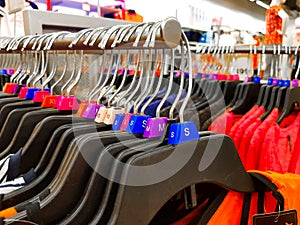 Different sized hanger with colourful dress size tags XL L M XS t shirts displayed in shop for sale