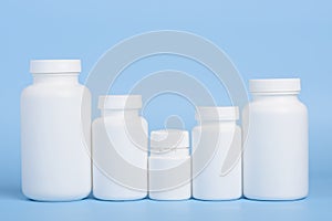 Different sizes of blank white plastic bottles of medicine pills or supplements in a row