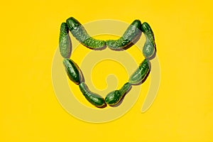 Different sizes forms cucumbers on a yellow background form a heart simbol