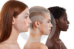 Different skin tones. Side view of three beautiful multicultural young women.Two caucasian and african half naked women photo