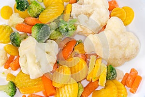 Different sliced frozen vegetables on dish close-up