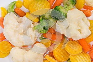 Different sliced frozen vegetables on dish, top view close-up