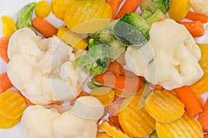 Different sliced frozen vegetables on dish, top view close-up photo