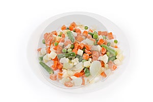 Different sliced frozen vegetables on white dish on white background photo