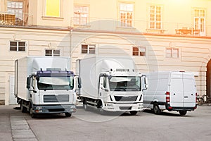 Different small and medium courier service  trucks and van at building courtyard. City delivery cargo shipping company vehilcles