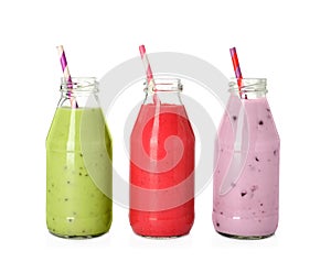 Different smoothies in glass bottles on white background