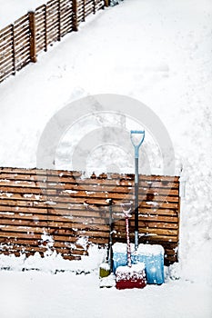 Different snow shovels or pushers standing on the fence, snowy background