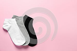 Different socks on pink background, flat lay. Space for text